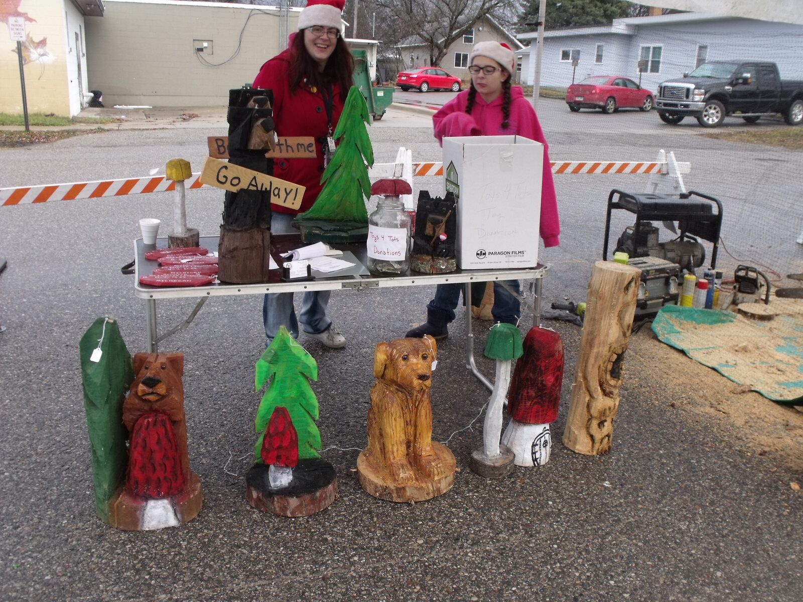 Chainsaw-carved bears, trees and a mushroom on display at a carver's table along the street