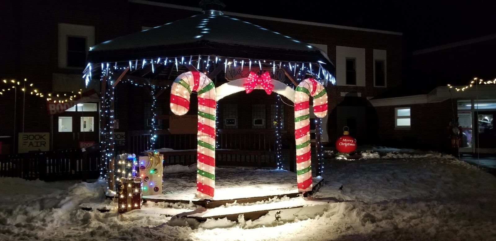 The candy-cane gazebo glowing with lights on a snowy night on the CRAF Center lawn