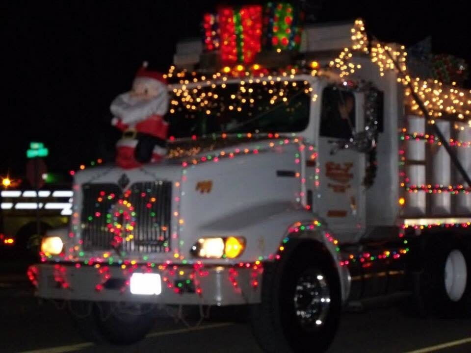 A truck outlined in red, green and white lights, with Santa riding on the front, in the parade
